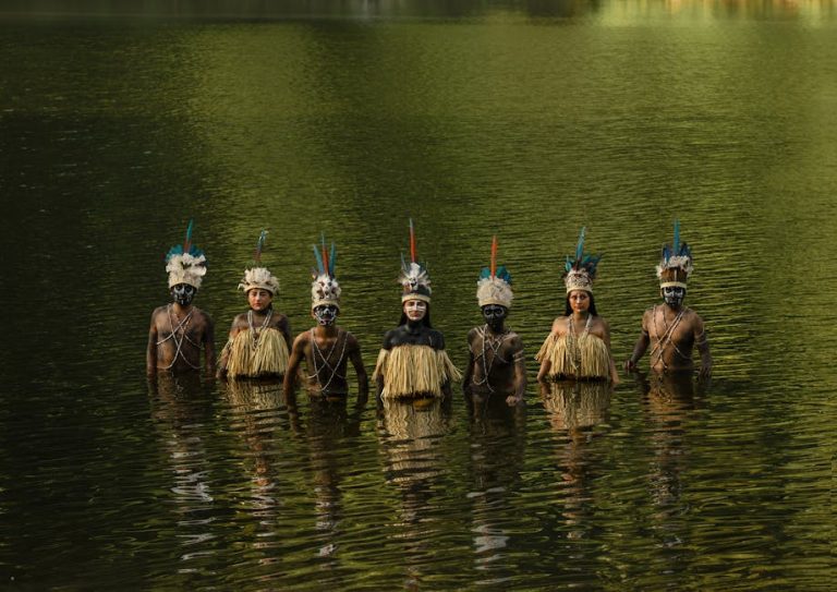 Tribal members in traditional attire stand in water, Tingo María, Peru.