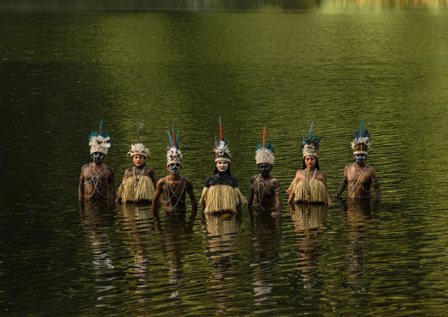 Tribal members in traditional attire stand in water, Tingo María, Peru.