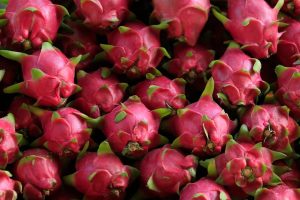 Close-up of vibrant pink dragon fruits stacked together, showcasing their unique texture and freshness.